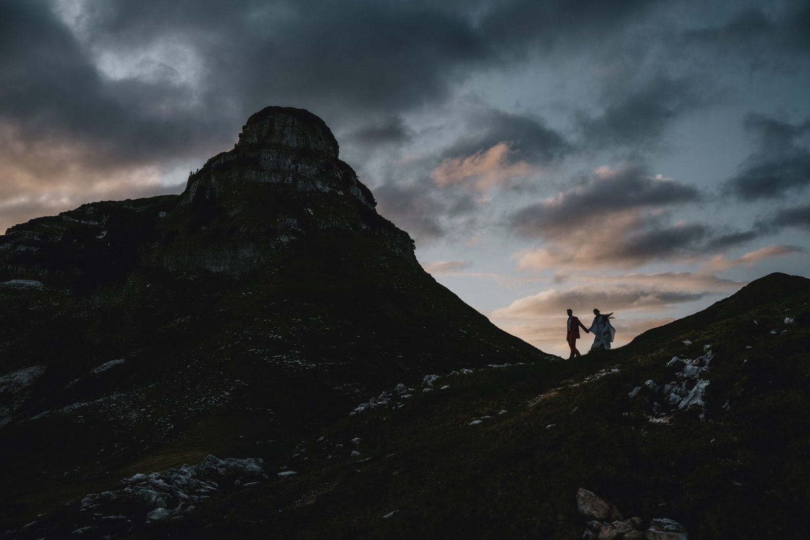 Paar als Silhouette auf einem Felsgrat unter eindrucksvollem Abendhimmel.
