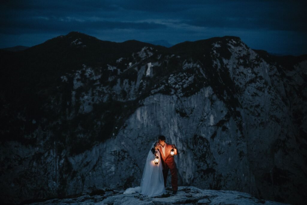 Elias and Wendy holding a warm light beneath a steep mountain face at dusk.
