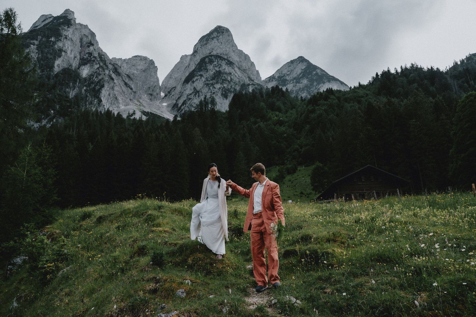 Elias und Wendy gehen Hand in Hand durch eine Bergwiese.