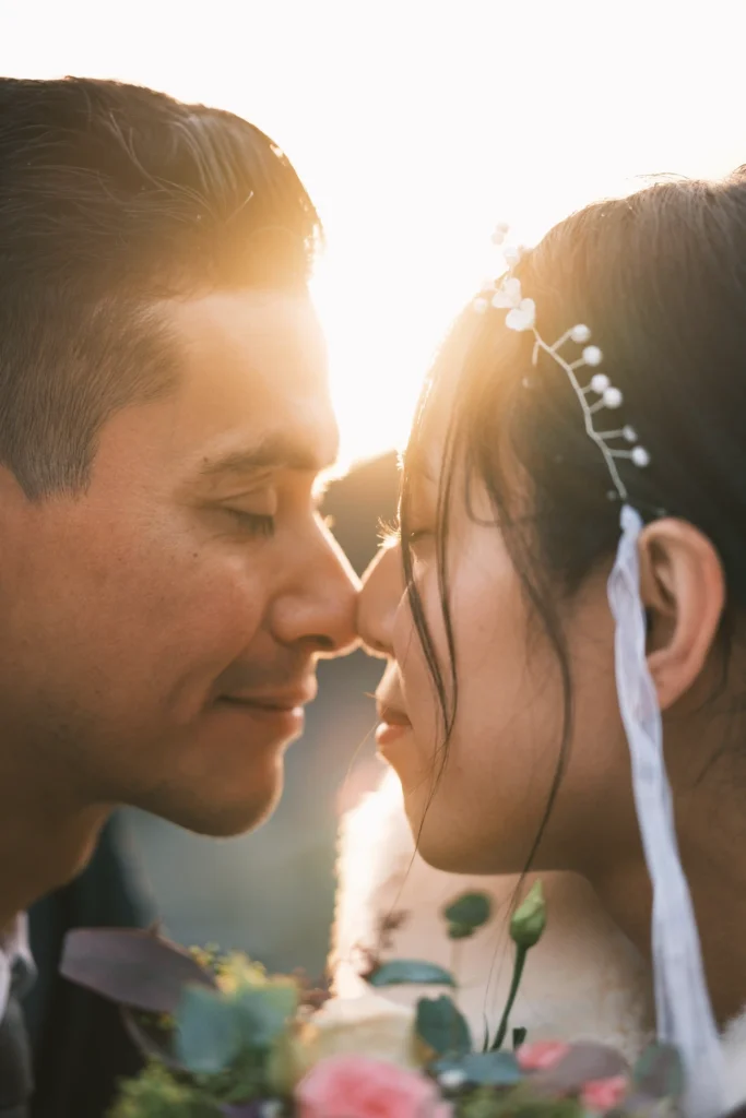 Close portrait of a couple touching foreheads with sunlight between their faces.