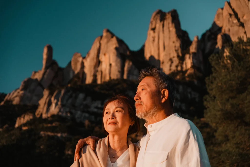 Couple embracing beneath sunlit rock towers.