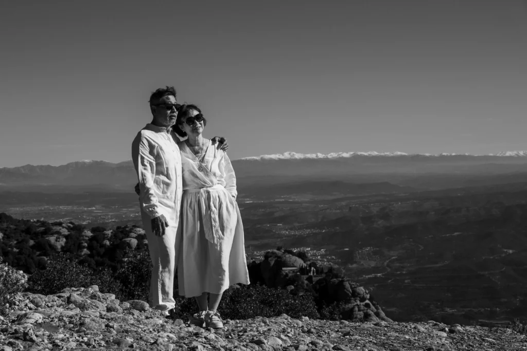 Black-and-white photograph of a couple at a viewpoint above a broad valley.