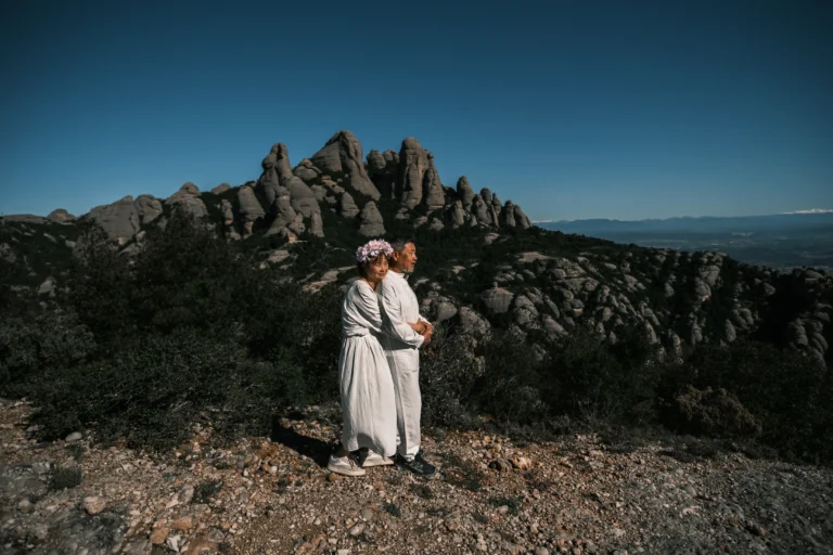 Couple holding each other on a plateau beneath rock towers.