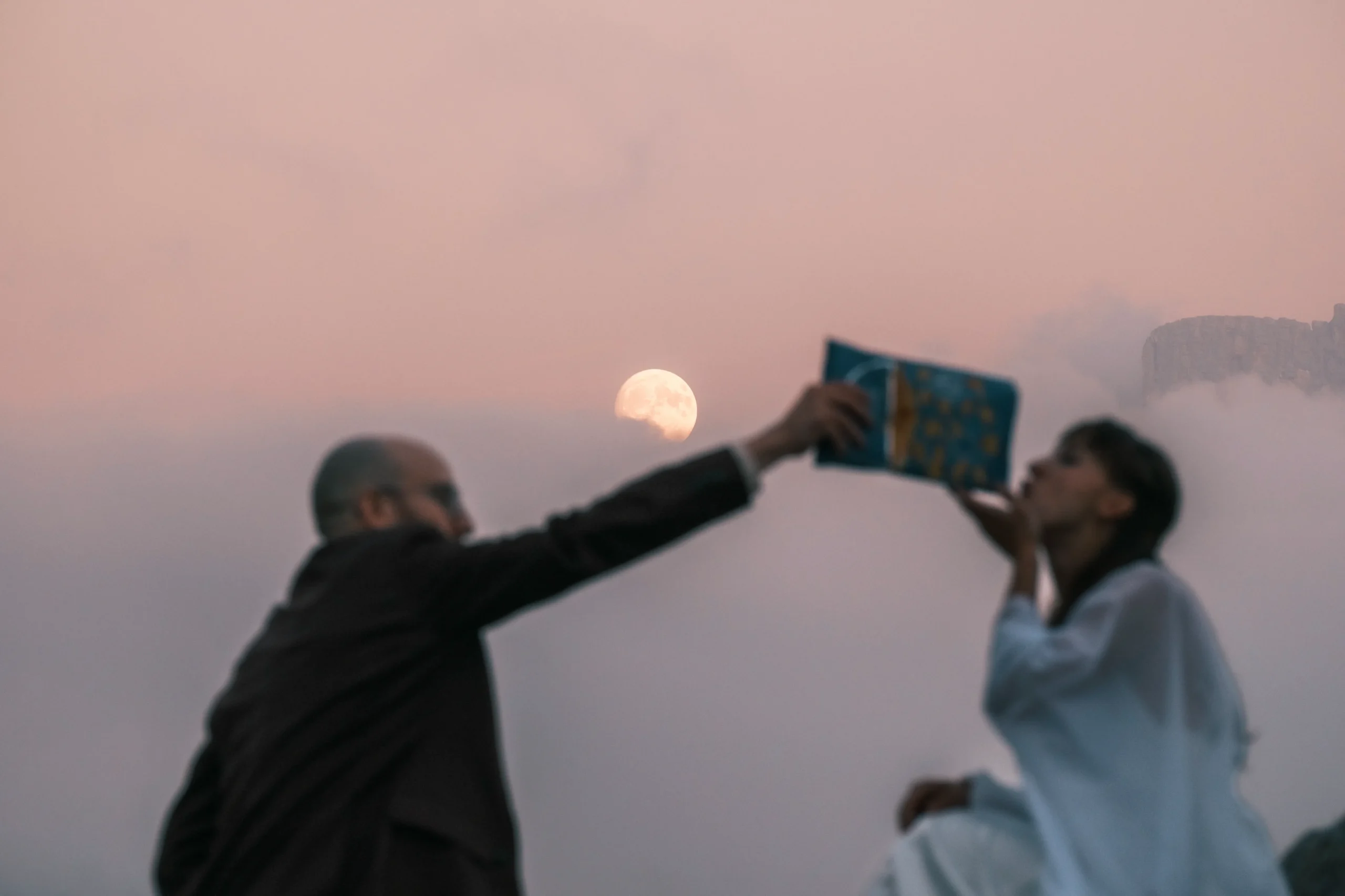 Paar hebt in der Dämmerung unter dem Mond gemeinsam ein kleines Buch.