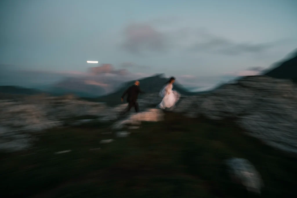 Blurred evening photograph of a couple moving across a mountain ridge.