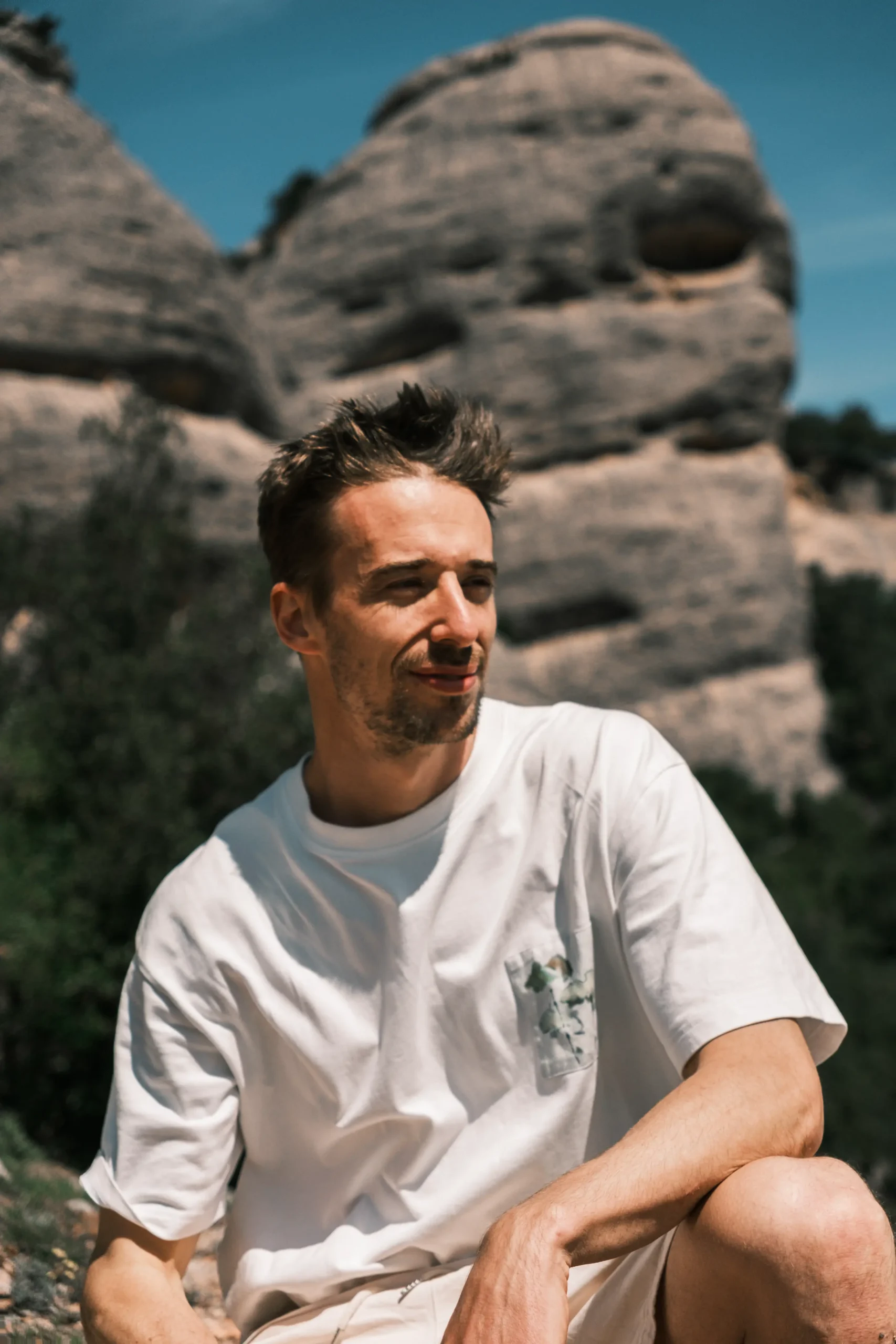 Elias sitzt zwischen sonnenbeschienenen Felsformationen.