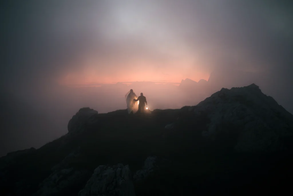 Distant couple with a lantern silhouetted against the last light on a mountain ridge.