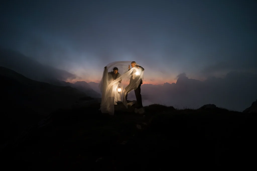 Couple beneath a flowing veil, illuminated by a lantern at dusk.